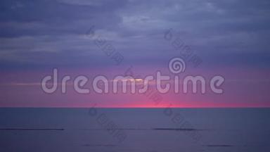 令人惊叹的黑暗风景，生动的深红色日落，在波罗的海有紫色和洋红色，在小太阳下。